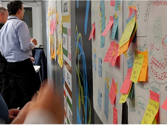 Nova Scotia Health vaccination-uptake workshop participants reviewing a dense wall of service-design notes